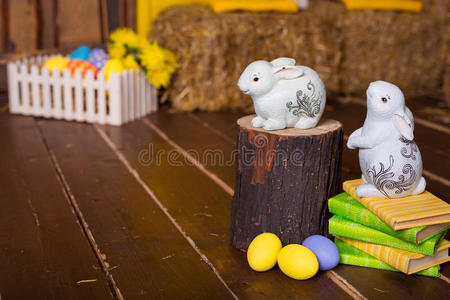 复活节背景，五颜六色的鸡蛋，白色的兔子和黄色的花在旧木头上。