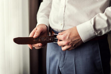 商人戴上皮带. 男人戴上棕色腰带. 集中精力照片