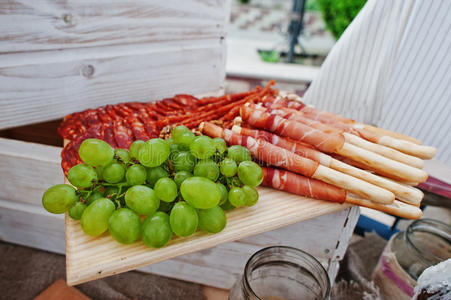 婚礼餐饮桌上的木制木板上有绿色葡萄和火腿棒。