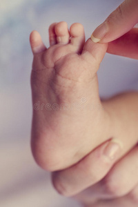 特写母亲的手，抱着可爱的小婴儿脚，展示婴儿的脚。 选择性聚焦。 色调。