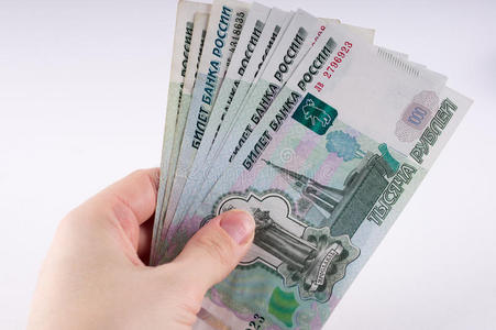 一只手拿着一堆一千美元的卢布钞票. 俄罗斯铜照片