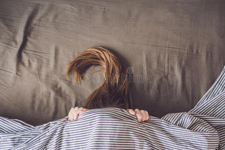 美丽的年轻女人躺在床上睡觉,俯视图. 没有足够的睡眠概念照片