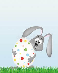 复活节兔子拿着一个大装饰的鸡蛋。 草地上的兔子。 贺卡