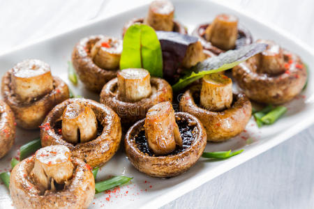 在白色盘子上烤香皮翁白蘑菇,配上草药和香料.