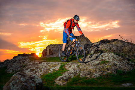骑山地自行车的人在春天的岩石小径上美丽的日落.