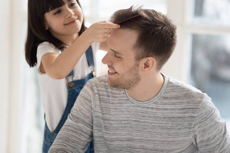 学龄前可爱的小女儿给父亲梳头照片