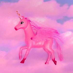 粉红色天空中的独角兽玩具。梦的概念