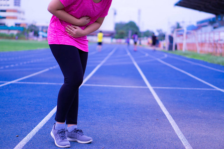 Sport girl holding abdomen with her hands in stomach pain after 