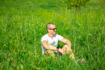戴墨镜坐在草地上的男人
