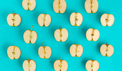 Fruit pattern of apple halves on blue background. Flat lay, top 