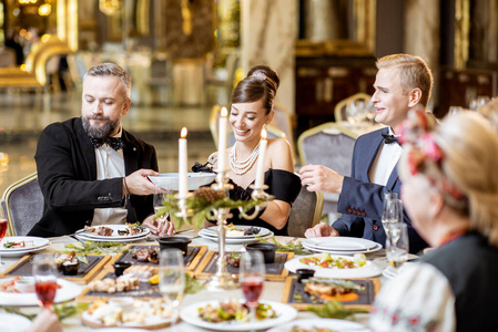 Elegantly dressed people having a festive dinner indoors