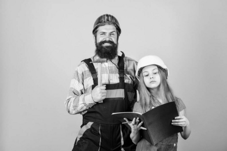 父亲留胡子的男子和女儿的安全帽头盔制服翻新家。家装活动。女孩计划翻新。儿童改造室。家庭装修房子。小帮手