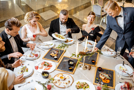 Elegantly dressed people having a festive dinner indoors