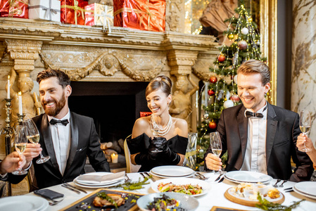 Elegantly dressed people having a festive dinner indoors