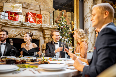 Elegantly dressed people having a festive dinner indoors