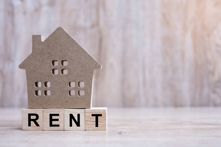 Wood block with RENT text and house model on wooden background. 