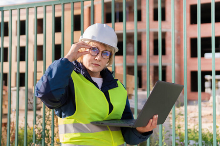 一位女建筑工人在建筑工地检查砖造的房子