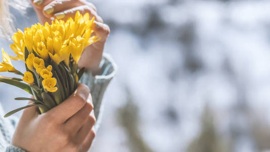 woman with a yellow bouquet of spring flowers in her hands on a 