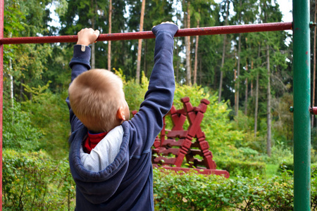 小男孩在操场上的单杠上.照片