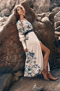 beautiful young woman in elegant stylish dress on stone beach 