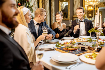 Elegantly dressed people having a festive dinner indoors