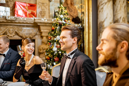 Elegantly dressed people having a festive dinner indoors