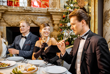 Elegantly dressed people having a festive dinner indoors