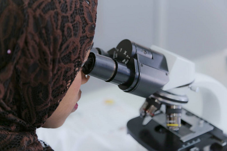 年轻的非洲穆斯林女科学家透过显微镜观察