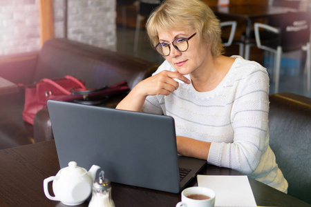 一个拿着笔记本电脑的女人在办公室的咖啡馆工作，她是个自由职业者。