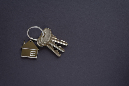 深灰色背景的房子钥匙和钥匙扣