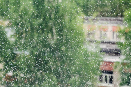 雨滴落在背景多云的窗玻璃表面。在多云背景下孤立的雨滴的自然模式。