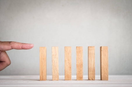 part of human finger push wooden domino on table 