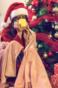 坐在圣诞树旁喝热茶的女人