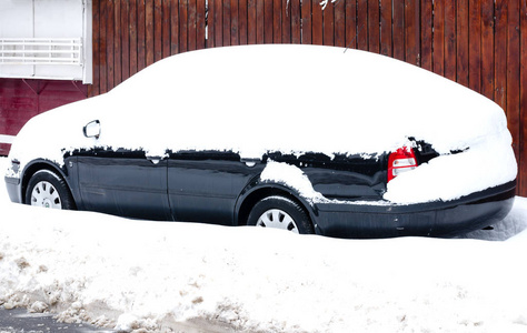 暴风雪过后，街道上被雪覆盖的汽车，背景是木栅栏