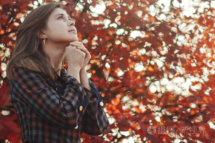 一位年轻女子在大自然中祈祷的画像女孩双手合十在下巴上感谢上帝与