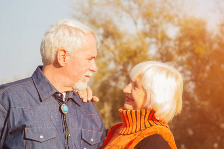 秋日坐在长凳上的幸福老人.放松的老年夫妇坐在公园的长椅上.