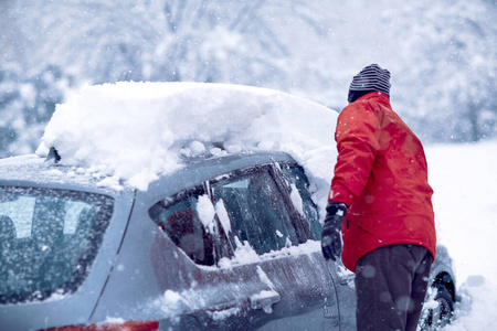 汽车陷在雪里了。冬天，一个男人在刷汽车上的雪