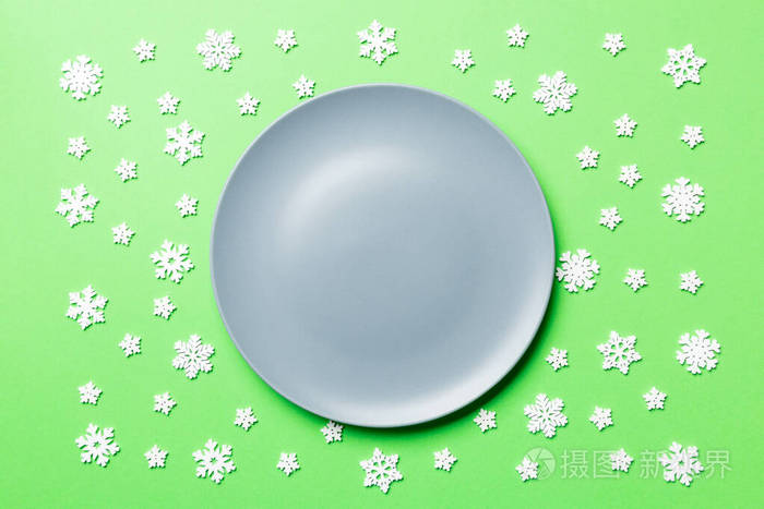彩色背景下被雪花包围的空盘子的俯视图新年晚餐概念