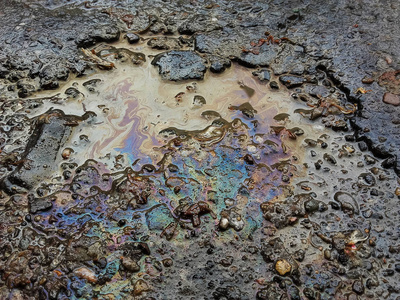 Closeup spots of gasoline in water on street 