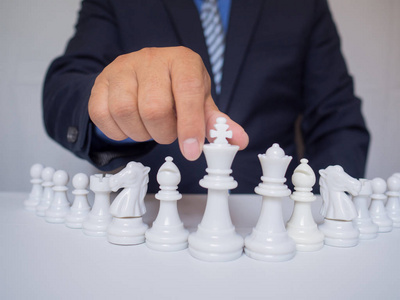 商人用白色背景在棋盘上移动棋子，向成功理念挑战商业战略规划