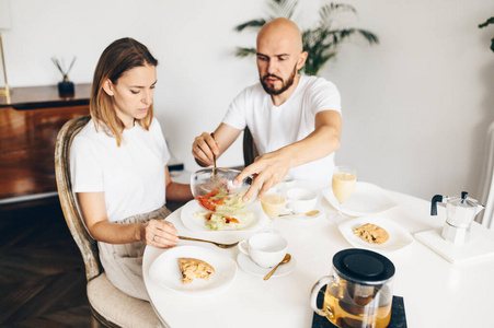 Young happy couple having breakfast at home together 