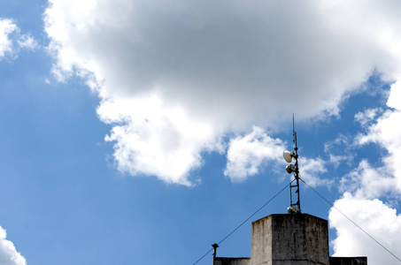 移动天线安装在一座古老的建筑物上，背景是蓝色多云的天空。