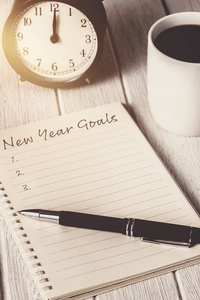 新年目标清单写在笔记本上，有闹钟，钢笔，