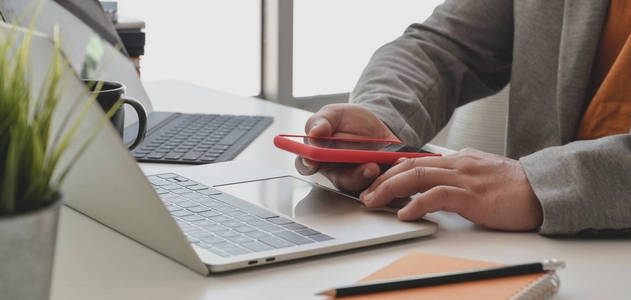 Cropped shot of businessman holding smartphone while working on 