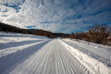 Empty snow covered road in winter landscape