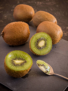 fresh kiwi with a tea spoon on stone background.	