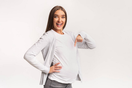 阳性的非洲裔孕妇手指着肚子年幼的女人起立和弄尖手指在复制品空间