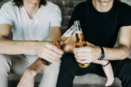 两个时髦的双胞胎兄弟在楼梯上喝啤酒玩得很开心照片