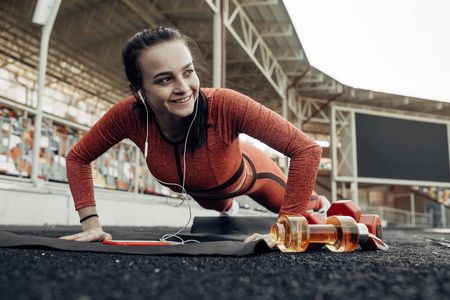 一位体育健身女孩的画像穿着时尚的运动服在城市体育场进行锻炼和训练，健康的生活方式理念