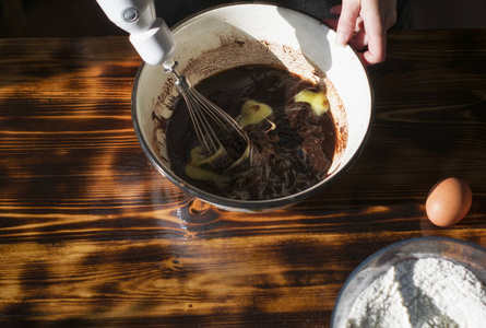 带搅拌器的巧克力面团。用搅拌器在碗里手工搅拌馅饼的配料。